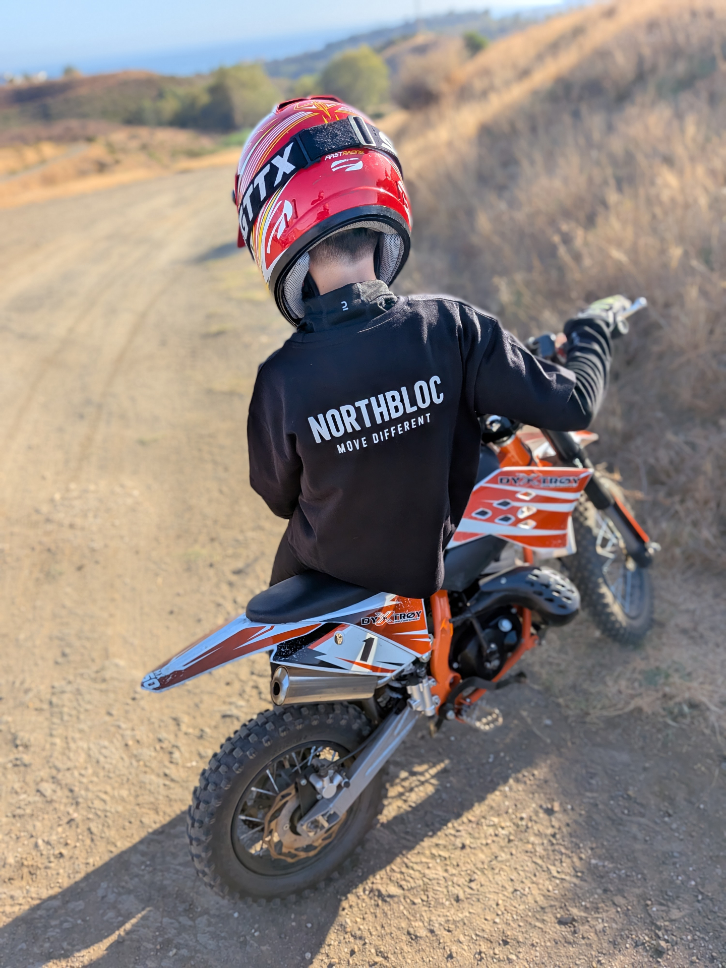 Rider on a dirt track wearing the black NORTHBLOC tee with the back print visible
